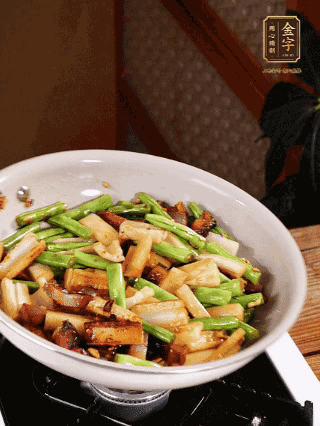 油熱下蒜末、干辣椒、醬肉煸炒出香味，依次下藕條、豆角翻炒均勻